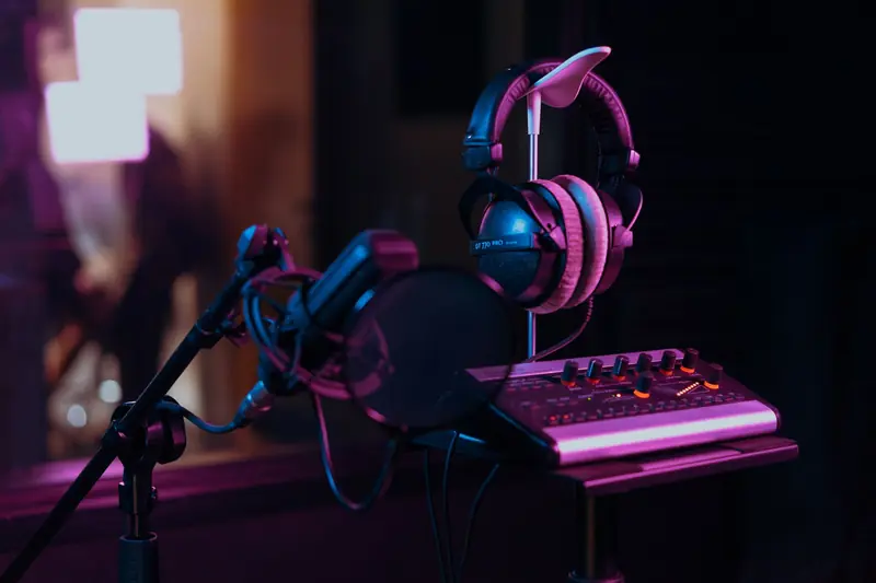 High-quality audio recording studio setup with a microphone, headphones, and mixer board in dim lighting