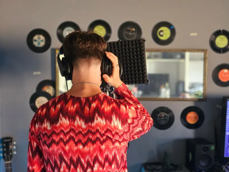 Back view of a young musician recording vocals in a home studio
