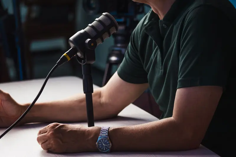 Close-up of a person recording a podcast in a studio, featuring a microphone and professional audio equipment