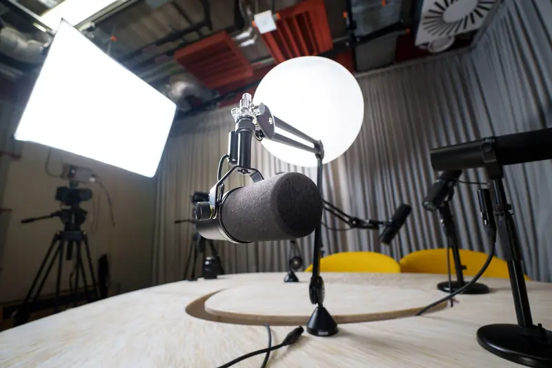 A modern podcast recording studio with microphones, chairs, and lighting equipment
