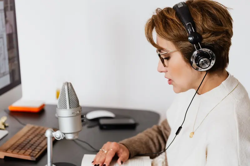 Woman with headphones speaking into a microphone in a modern home studio