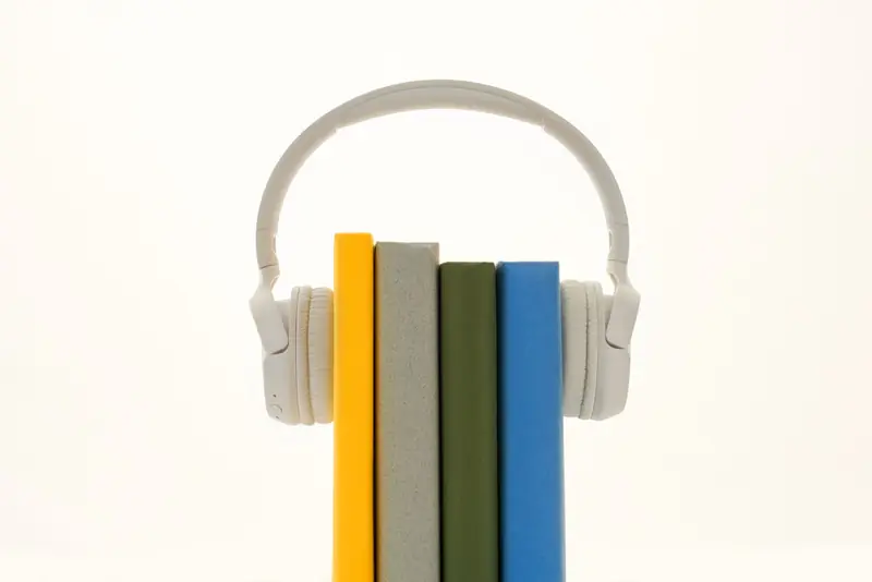 White headphones resting on colorful books, symbolizing modern audio technology