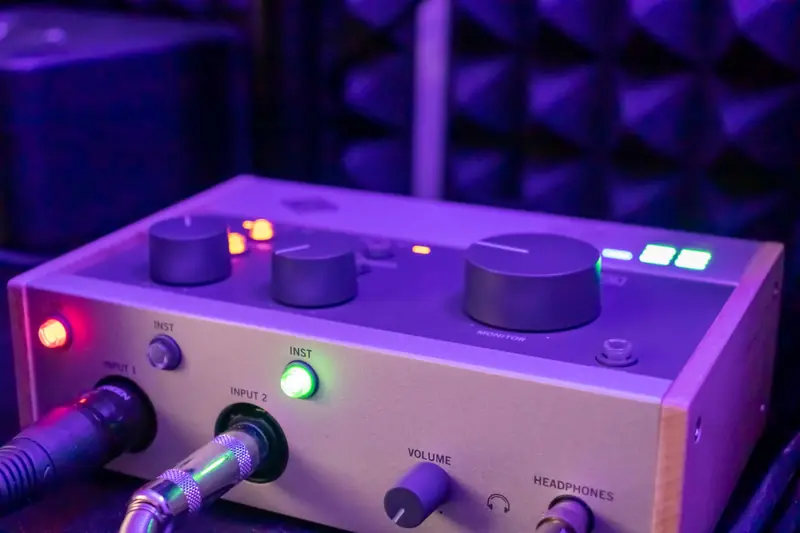 Detailed close-up of an audio interface with knobs and plugs in a recording studio setting