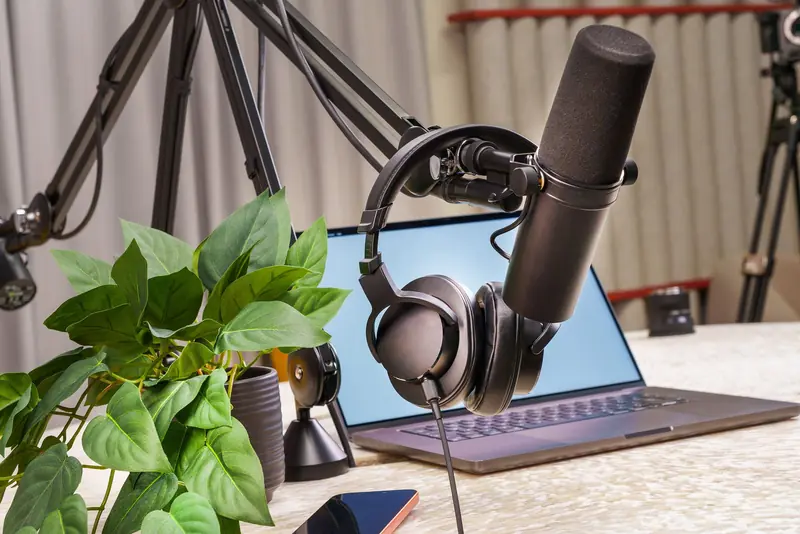 A modern podcast studio setup with a microphone, headphones, and laptop, ideal for media production and online broadcasting