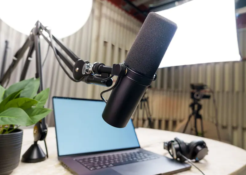 Professional podcast studio setup featuring a microphone, laptop, and headphones ready for recording