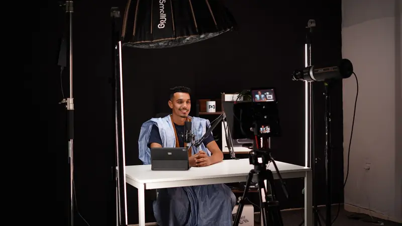 Young man recording a video in a professional studio with lighting and camera equipment